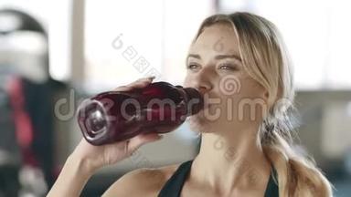口渴的女人在健身房健身训练后享受水。